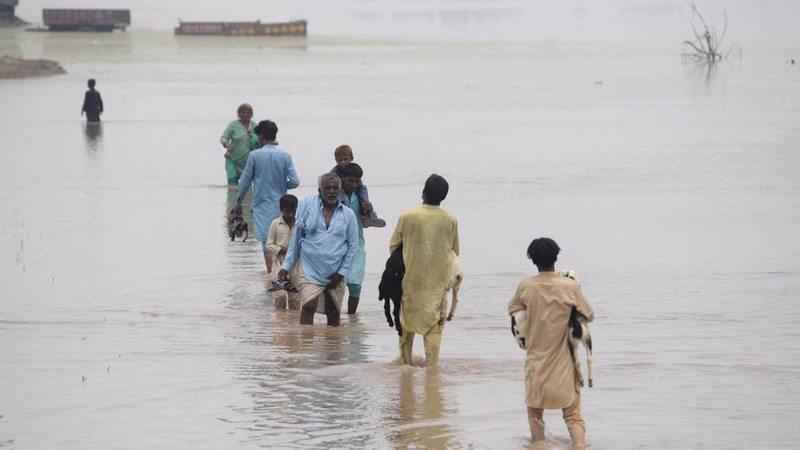 Orang-orang menyeberangi jalan yang tergenang air akibat hujan monsun di Muridke, Pakistan, 28 Juli 2026.