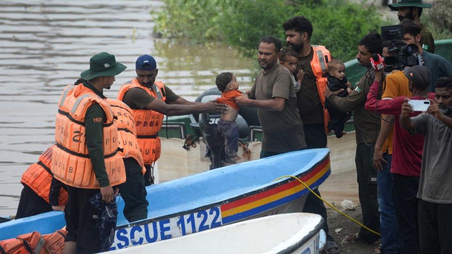 Para petugas Rescue 1122 memindahkan anak-anak setelah mereka, bersama keluarga mereka, dievakuasi dari daerah yang terendam banjir akibat hujan monsun, di Ferozwala, Pakistan, 28 Juli 2026.