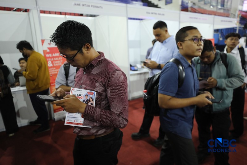 Pencari kerja mencari informasi lowongan pekerjaan pada kegiatan Job Fair yang digelar Pemkot Jakarta Timur di GOR Ciracas, Jakarta, Rabu (29/7/2026). (CNBC Indonesia/Tri Susilo)