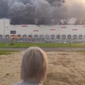 A woman looks on as smoke billows from a Wildberries warehouse after a fire broke out at the facility, in Ryazan region, Russia, July 29, 2026, in this still image obtained from a video. SOCIAL MEDIA/via REUTERS  THIS IMAGE HAS BEEN SUPPLIED BY A THI