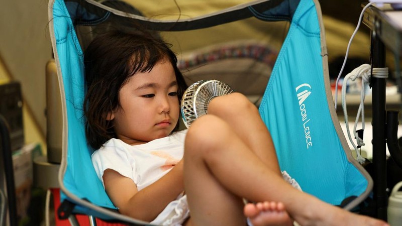 Tsugumi Shimada (3), putri Hirosuke Shimada, menggunakan kipas angin portabel di dalam tenda setelah gempa bumi berkekuatan 7,1 melanda prefektur Kumamoto selatan Jepang, di tengah pemadaman air di daerah tersebut selama gelombang panas, di Yatsushiro, Jepang, 30 Juli 2026. Khawatir akan gempa susulan, ia dan anggota keluarganya tinggal di tenda di depan rumah mereka.