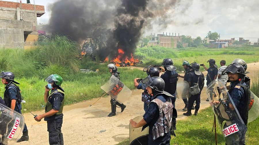 Anggota Kepolisian Nepal berdiri di samping sepeda motor yang terbakar sambil menunggu mobil pemadam kebakaran saat terjadi bentrokan antara dua komunitas di Siraha, Nepal, 30 Juli 2026.