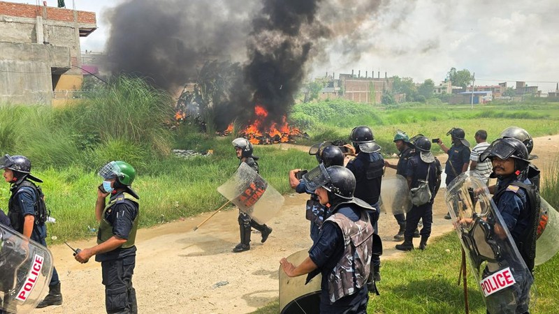 Anggota Kepolisian Nepal berdiri di samping sepeda motor yang terbakar sambil menunggu mobil pemadam kebakaran saat terjadi bentrokan antara dua komunitas di Siraha, Nepal, 30 Juli 2026.