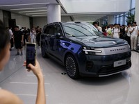 A woman takes photos of a Xiaomi SkyNomad N90 Max EREV (Extended-Range Electric Vehicle) on display before the car's launch event, in Xiaomi's industrial park, in Beijing, China July 30, 2026. REUTERS/Tingshu Wang