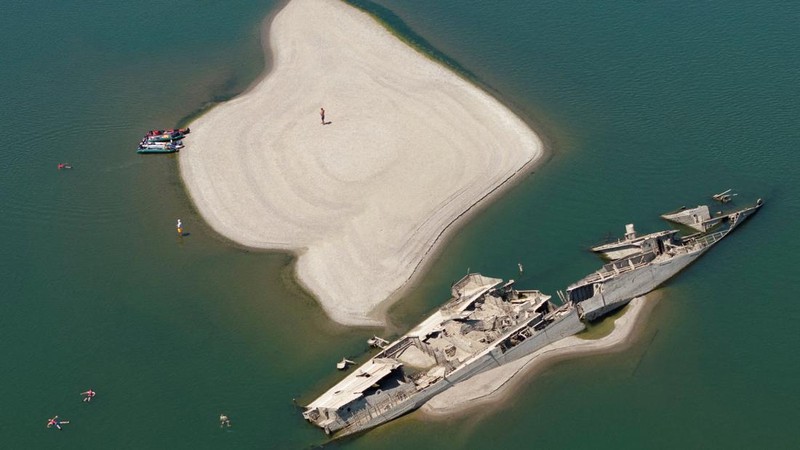 Sebuah tayangan drone menunjukkan orang-orang berenang di dekat kapal perang Jerman yang tenggelam dari Perang Dunia II, yang terlihat karena rendahnya permukaan Sungai Danube akibat kekeringan dan panas ekstrem, di Prahovo, Serbia, 30 Juli 2026.