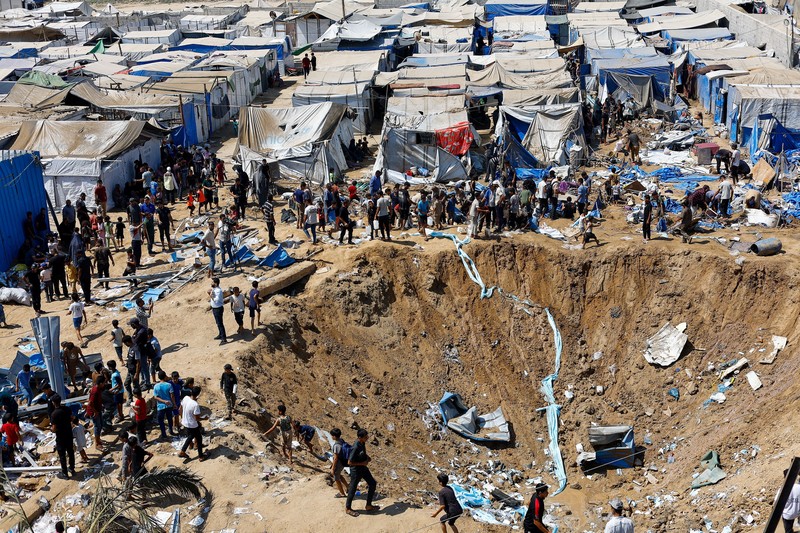 Palestinians inspect the site of an overnight Israeli strike on a medicine warehouse,  according to medics, next to tents sheltering displaced Palestinians, in Deir al-Balah, in the central Gaza Strip, August 1, 2026, residents had been pre-warned by the Israeli military to evacuate. REUTERS/Mahmoud Issa REFILE - ADDS INFORMATION