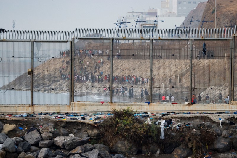 Migrants walk on the Moroccan side of the border, after mass crossings of migrants on foot and by sea from Morocco into Spanish territory, as seen from Cueta, Spain, August 1, 2026. REUTERS/Jon Nazca