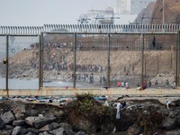 Migrants walk on the Moroccan side of the border, after mass crossings of migrants on foot and by sea from Morocco into Spanish territory, as seen from Cueta, Spain, August 1, 2026. REUTERS/Jon Nazca