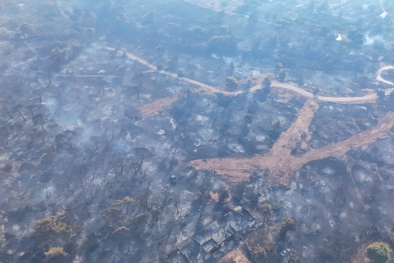 Seorang warga menyaksikan sebuah helikopter menjatuhkan air saat kebakaran hutan melanda lembah Megara, Yunani, 2 Agustus 2026. (REUTERS/Louisa Gouliamaki)
