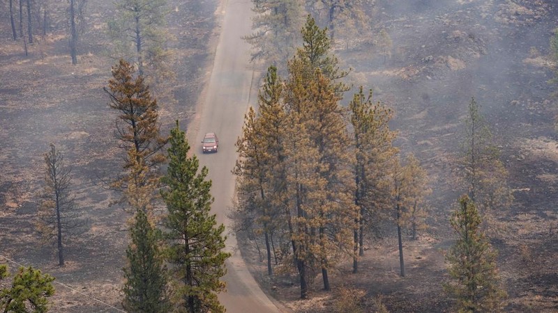 Sebuah kendaraan melintas saat asap mengepul dari Kebakaran Old Trails ketika kebakaran hutan melanda Spokane, Washington, AS, 2 Agustus 2026.
