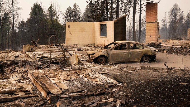 Sebuah kendaraan yang terbakar berada di antara reruntuhan rumah saat kebakaran hutan melanda Spokane, Washington, AS, 2 Agustus 2026.