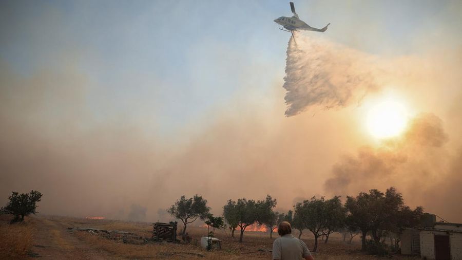 Seorang warga menyaksikan sebuah helikopter menjatuhkan air saat kebakaran hutan melanda lembah Megara, Yunani, 2 Agustus 2026. (REUTERS/Louisa Gouliamaki)