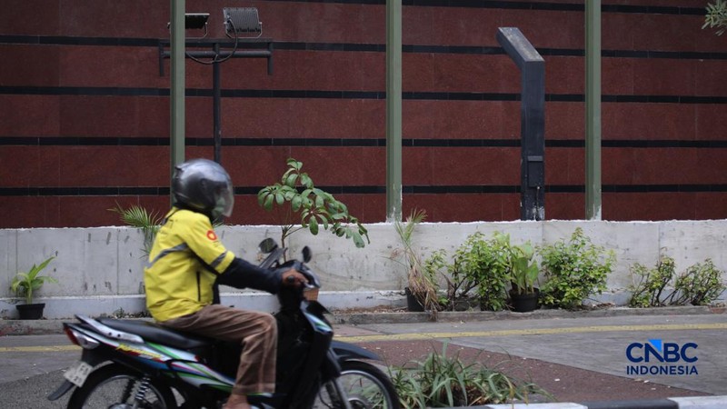 Warga melintas di samping pagar Blok M Plaza, Jakarta, Senin (3/8/2026). Polemik pemasangan pagar tinggi di sejumlah pusat perbelanjaan di Jakarta mencuri perhatian setelah beberapa mal memasang pagar besi yang mengelilingi area bangunan. (CNBC Indon