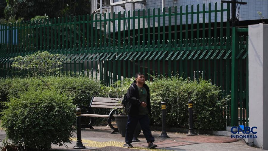 Warga melintas di samping pagar Blok M Plaza, Jakarta, Senin (3/8/2026). Polemik pemasangan pagar tinggi di sejumlah pusat perbelanjaan di Jakarta mencuri perhatian setelah beberapa mal memasang pagar besi yang mengelilingi area bangunan. (CNBC Indon