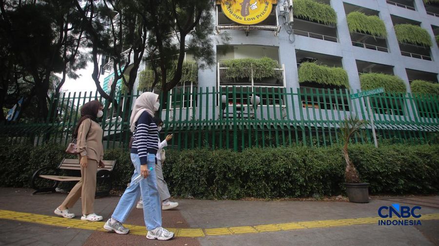 Warga melintas di samping pagar Blok M Plaza, Jakarta, Senin (3/8/2026). Polemik pemasangan pagar tinggi di sejumlah pusat perbelanjaan di Jakarta mencuri perhatian setelah beberapa mal memasang pagar besi yang mengelilingi area bangunan. (CNBC Indon