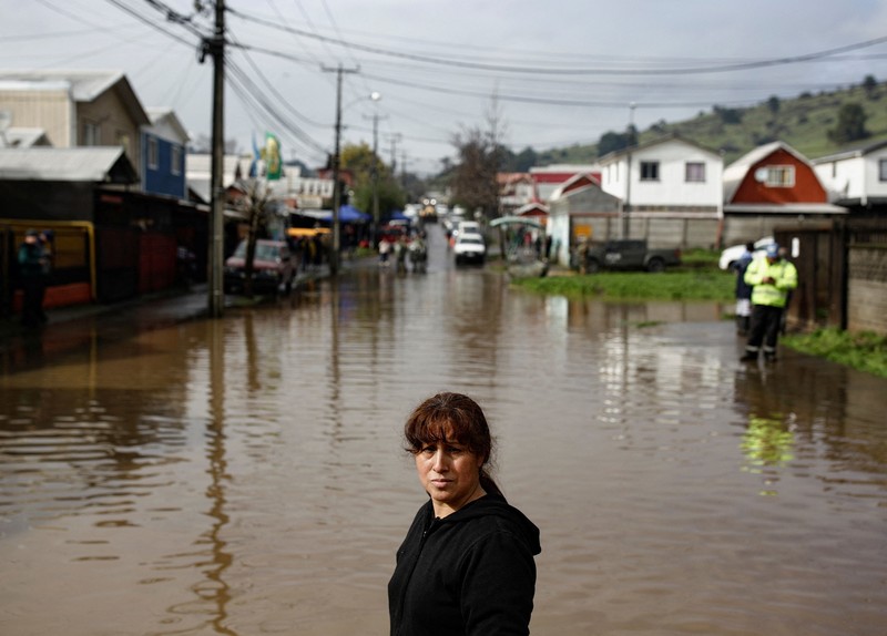 Nancy Badilla berjalan di sepanjang jalan yang tergenang air setelah badai membawa hujan lebat dan menyebabkan banjir di Angol, Chili, 3 Agustus 2026. (REUTERS/Juan Gonzalez)