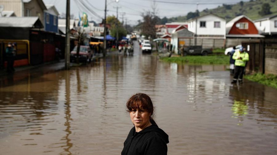 Nancy Badilla melangkah di sepanjang jalan nan tergenang air setelah angin besar membawa hujan lebat dan menyebabkan banjir di Angol, Chili, 3 Agustus 2026. (REUTERS/Juan Gonzalez)