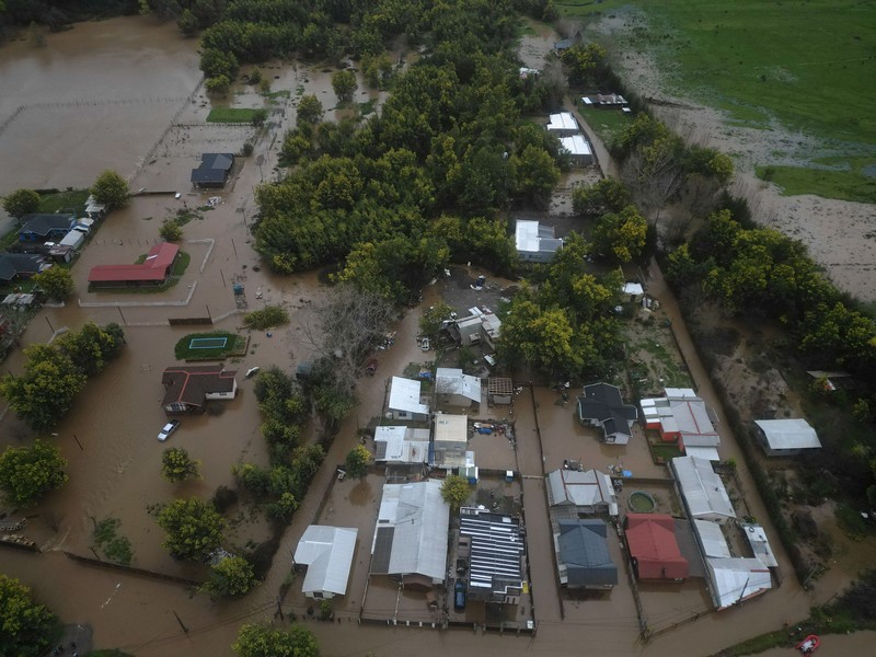 Nancy Badilla berjalan di sepanjang jalan yang tergenang air setelah badai membawa hujan lebat dan menyebabkan banjir di Angol, Chili, 3 Agustus 2026. (REUTERS/Juan Gonzalez)