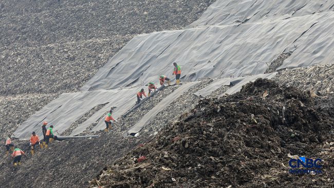 Sejumlah petugas TPST Bantargebang memasang lapisan geomembran di tempat pemrosesan atau pembuangan akhir (TPA) sampah Bantargebang, Bekasi, Jawa Barat, Selasa, (4/8/2026). (CNBC Indonesia/Muhammad Sabki)