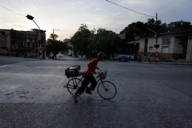 Seorang pria mengendarai sepeda sambil menyeberang jalan saat jaringan listrik nasional Kuba mengalami gangguan pada hari Minggu, kegagalan jaringan listrik nasional keempat dalam waktu kurang dari sebulan, di Havana, Kuba, 3 Agustus 2026. (REUTERS/Norlys Perez)