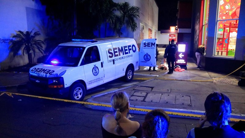 Sejumlah warga berdiri di balik garis polisi saat petugas forensik dan aparat kepolisian bekerja di tempat kejadian perkara—lokasi di mana Cesar Gastelum, seorang *influencer* media sosial asal Meksiko yang dikenal lewat video-video komedinya dan memiliki hampir 600.000 pengikut di TikTok, ditembak hingga tewas saat sedang melakukan siaran langsung bersama teman-temannya di luar sebuah restoran cepat saji di Culiacan, negara bagian Sinaloa, Meksiko, pada 4 Agustus 2026.