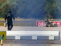 Seorang petugas polisi yang mengenakan pakaian pelindung berjalan di samping robot penjinak bahan peledak (EOD) di Bandara Leipzig/Halle di Schkeuditz, Jerman, pada 5 Agustus 2026. Langkah ini diambil setelah polisi menyatakan bahwa ahli bahan peleda