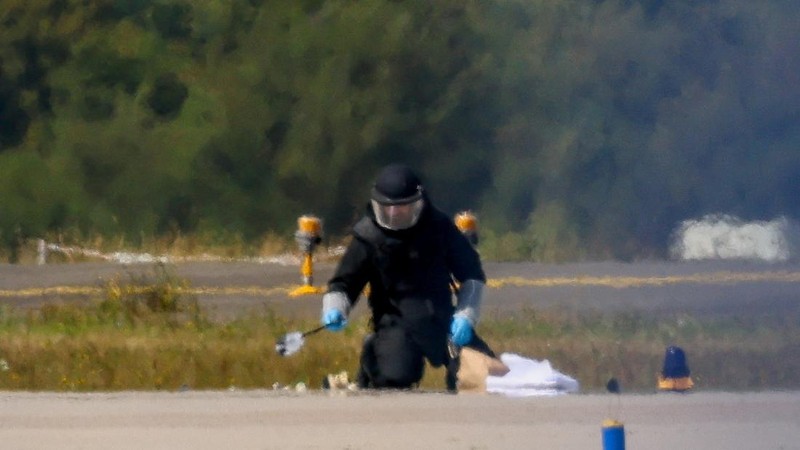 Seorang petugas polisi yang mengenakan pakaian pelindung sedang bertugas di Bandara Leipzig/Halle di Schkeuditz, Jerman, pada 5 Agustus 2026. Hal ini terjadi setelah polisi menyatakan bahwa tim ahli bahan peledak memeriksa sebuah pesawat nirawak (drone) di dekat landasan pacu, serta menyusul insiden di mana sebuah pesawat kargo DHL menabrak objek tak dikenal saat sedang menanjak meninggalkan bandara pada malam sebelumnya, yang memicu pendaratan tak terjadwal di Hanover, menurut sumber yang mengetahui peristiwa tersebut.