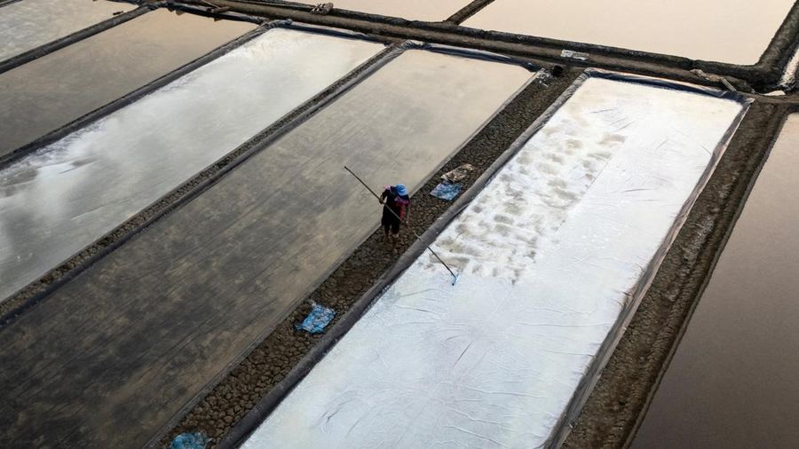 Tampilan dari drone memperlihatkan seorang petani sedang menyiapkan garam kristal di dasar tambak saat masa panen di Desa Pengarengan, Cirebon, Provinsi Jawa Barat, Indonesia, pada 30 Juli 2026.