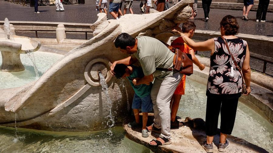 Seorang pria menyejukkan tubuh anaknya dengan air dari Fontana della Barcaccia saat gelombang panas melanda Roma, Italia, pada 6 Agustus 2026.