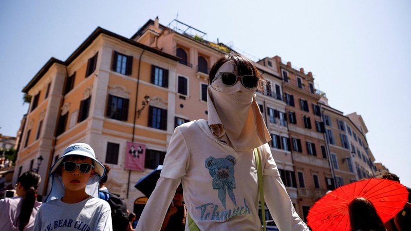 Seorang wanita yang mengenakan kacamata hitam dan penutup wajah berjalan bersama seorang anak di dekat Spanish Steps saat gelombang panas melanda Roma, Italia, pada 6 Agustus 2026.