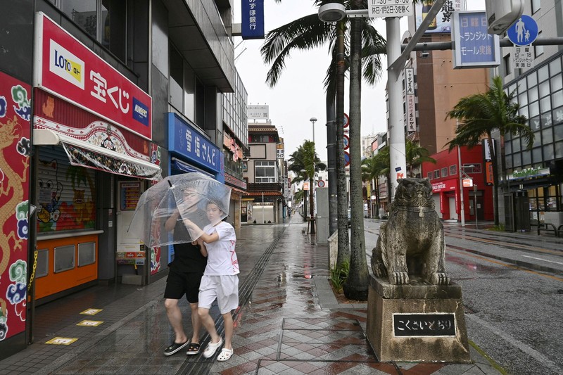 Orang-orang berjalan membawa payung di Naha, Prefektur Okinawa, Jepang, pada 7 Agustus 2026. (Kyodo/via REUTERS)