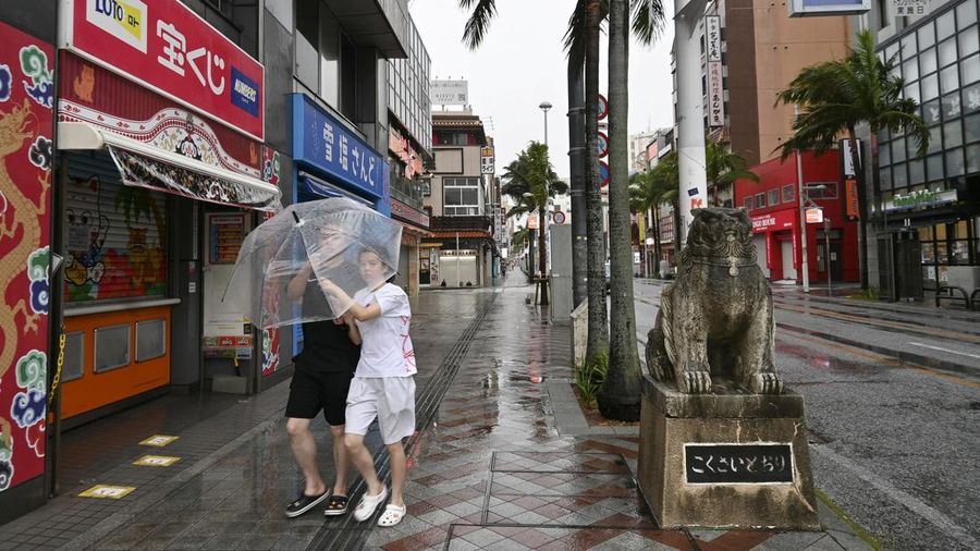 Orang-orang berjalan membawa payung di Naha, Prefektur Okinawa, Jepang, pada 7 Agustus 2026. (Kyodo/via REUTERS)