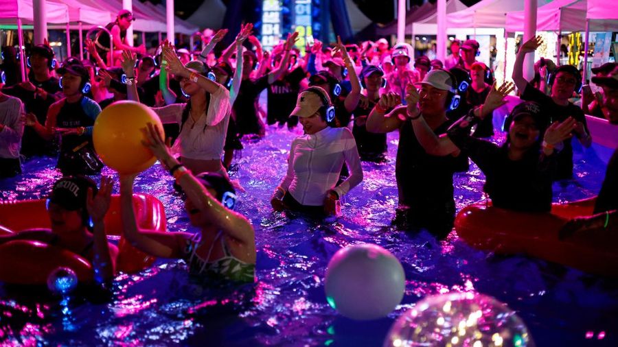 Orang-orang yang mengenakan headphone nirkabel menari di dalam kolam untuk menyejukkan diri saat acara "Silent Evening Pool Party" di Alun-alun Gwanghwamun di tengah gelombang panas di Seoul, Korea Selatan, pada 7 Agustus 2026. (REUTERS/Kim Soo-hyeon