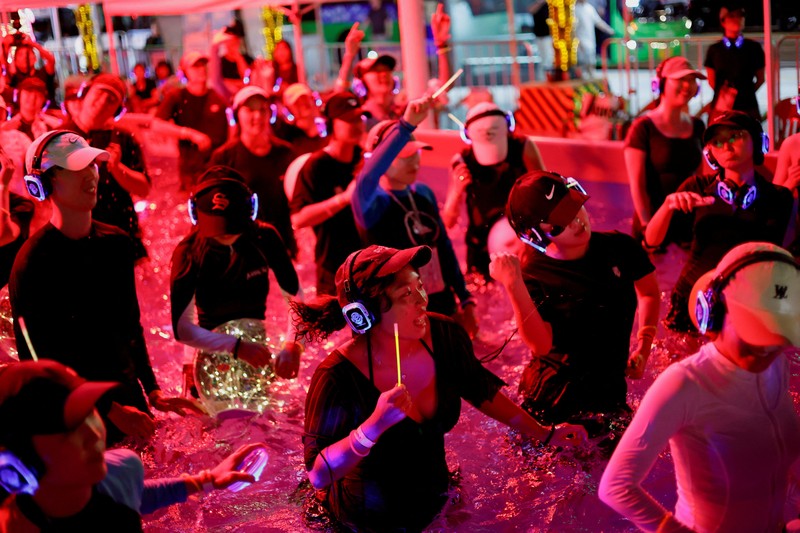 Orang-orang yang mengenakan headphone nirkabel menari di dalam kolam untuk menyejukkan diri saat acara