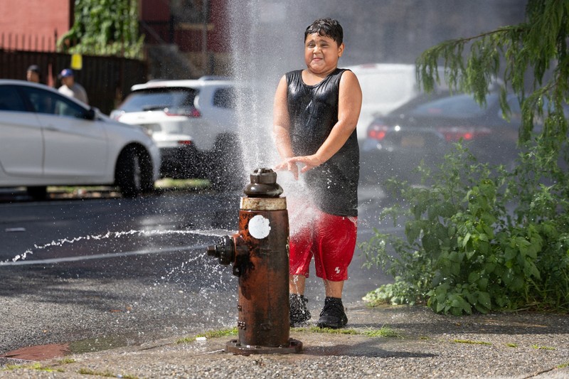 Seorang pejalan kaki menggunakan kipas tangan saat gelombang panas melanda New York City, AS, pada 7 Agustus 2026. (REUTERS/Jeenah Moon)