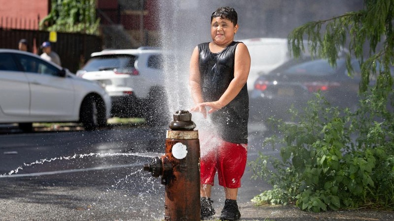 Seorang anak laki-laki mendinginkan diri dengan air dari hidran kebakaran saat gelombang panas melanda New York City, AS, pada 7 Agustus 2026.