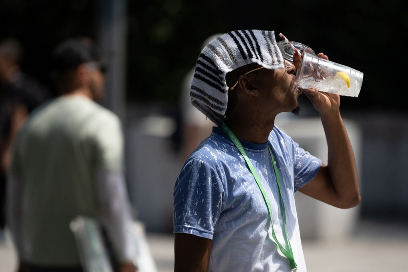 Seorang pejalan kaki menggunakan kipas tangan saat gelombang panas melanda New York City, AS, pada 7 Agustus 2026. (REUTERS/Jeenah Moon)