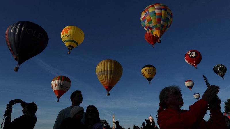 Warga menyaksikan balon udara terbang saat peluncuran massal di acara tahunan Bristol International Balloon Fiesta di Bristol, Inggris, pada 8 Agustus 2026. (REUTERS/Toby Melville)