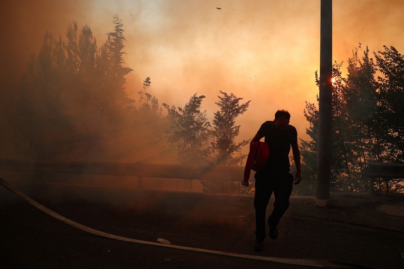 Warga setempat menyaksikan asap membubung dari kebakaran hutan yang melanda Kruja, Albania, pada 9 Agustus 2026. (REUTERS/Florion Goga)
