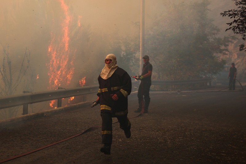 Warga setempat menyaksikan asap membubung dari kebakaran hutan yang melanda Kruja, Albania, pada 9 Agustus 2026. (REUTERS/Florion Goga)