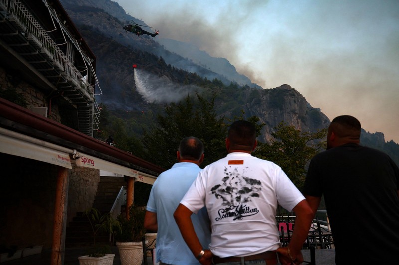 Warga setempat menyaksikan asap membubung dari kebakaran hutan yang melanda Kruja, Albania, pada 9 Agustus 2026. (REUTERS/Florion Goga)