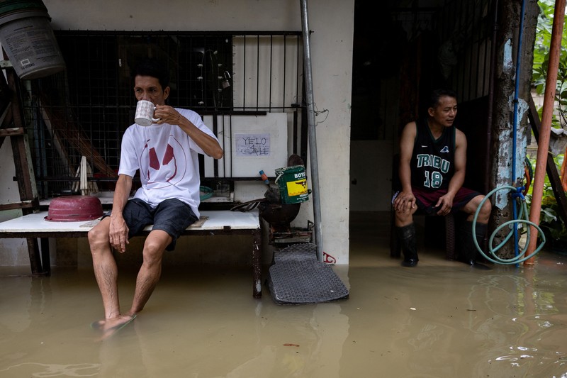 Warga yang membawa barang-barang mereka berjalan menerjang banjir di sebuah desa di tengah hujan monsun barat daya di Bagong Silangan, Quezon City, Filipina, pada 10 Agustus 2026. (REUTERS/Eloisa Lopez)