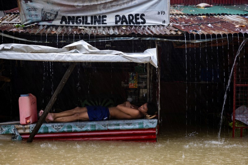 Warga yang membawa barang-barang mereka berjalan menerjang banjir di sebuah desa di tengah hujan monsun barat daya di Bagong Silangan, Quezon City, Filipina, pada 10 Agustus 2026. (REUTERS/Eloisa Lopez)