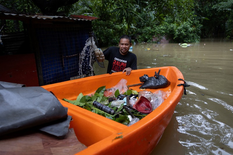 Warga yang membawa barang-barang mereka berjalan menerjang banjir di sebuah desa di tengah hujan monsun barat daya di Bagong Silangan, Quezon City, Filipina, pada 10 Agustus 2026. (REUTERS/Eloisa Lopez)
