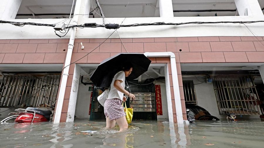 Seorang warga menerjang banjir di sebuah kompleks perumahan setelah hujan deras saat Topan Dolphin mendekat, di Shanghai, Tiongkok, 9 Agustus 2026.