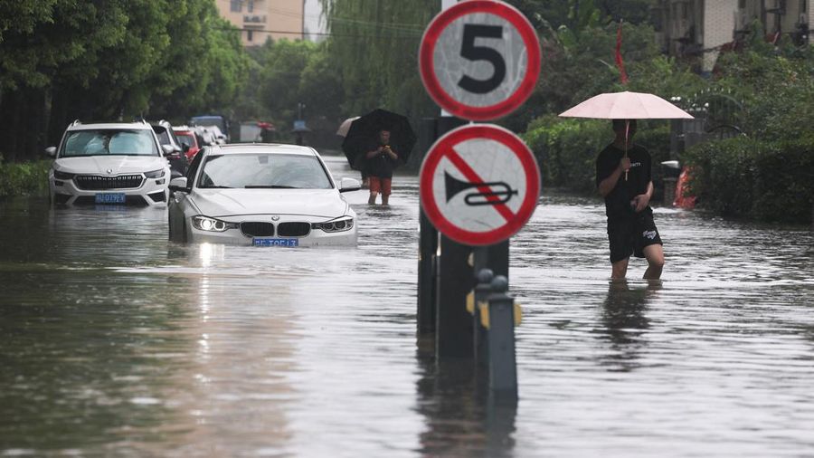Warga berjalan menerjang jalanan yang tergenang banjir setelah Topan Dolphin membawa hujan lebat ke Shanghai, Tiongkok, pada 10 Agustus 2026.
