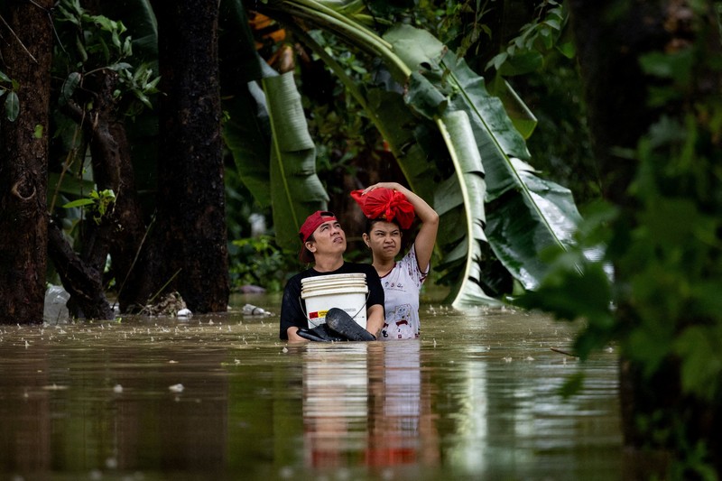Warga yang membawa barang-barang mereka berjalan menerjang banjir di sebuah desa di tengah hujan monsun barat daya di Bagong Silangan, Quezon City, Filipina, pada 10 Agustus 2026. (REUTERS/Eloisa Lopez)