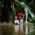 Warga yang membawa barang-barang mereka berjalan menerjang banjir di sebuah desa di tengah hujan monsun barat daya di Bagong Silangan, Quezon City, Filipina, pada 10 Agustus 2026. (REUTERS/Eloisa Lopez)