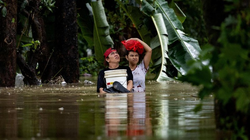 Warga yang membawa barang-barang mereka berjalan menerjang banjir di sebuah desa di tengah hujan monsun barat daya di Bagong Silangan, Quezon City, Filipina, pada 10 Agustus 2026. (REUTERS/Eloisa Lopez)