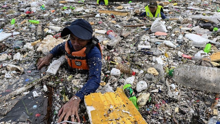 Para pekerja mengumpulkan sampah yang terbawa arus ke sungai di tengah hujan deras akibat angin muson barat daya di dekat Gereja Baclaran di Kota Paranaque, Metro Manila, Filipina, 11 Agustus 2026.